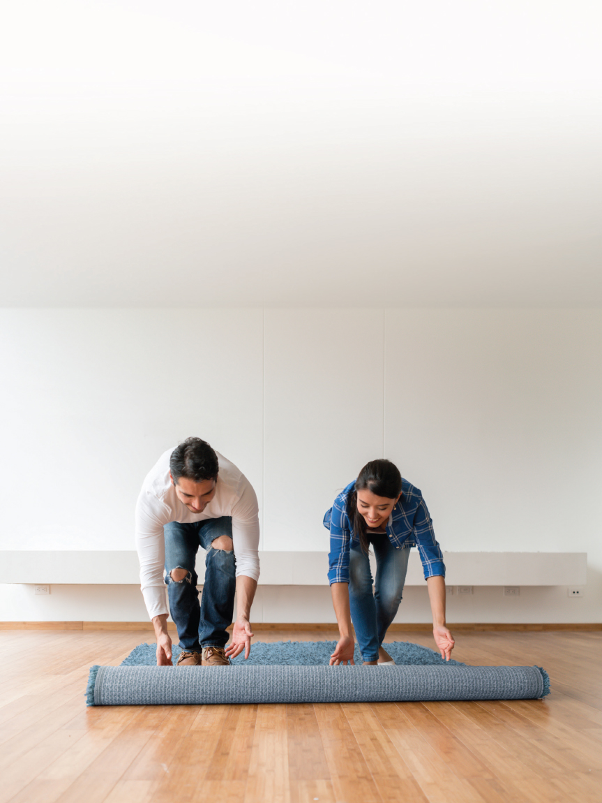 Couple rolling out area rug on new Hardwood Floor